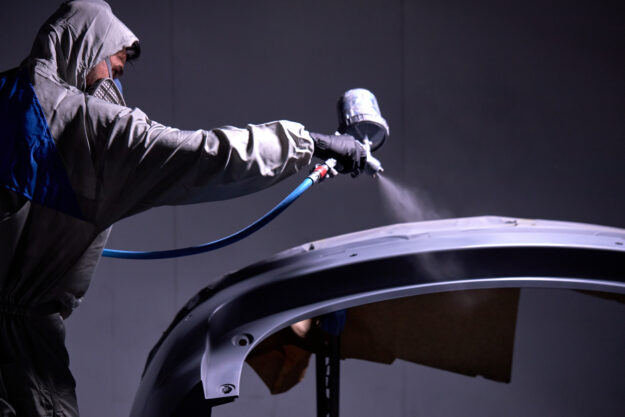 confident mechanic worker painting a car in the service Nasslackierung